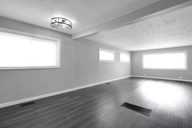 spare room featuring a textured ceiling, baseboards, and visible vents