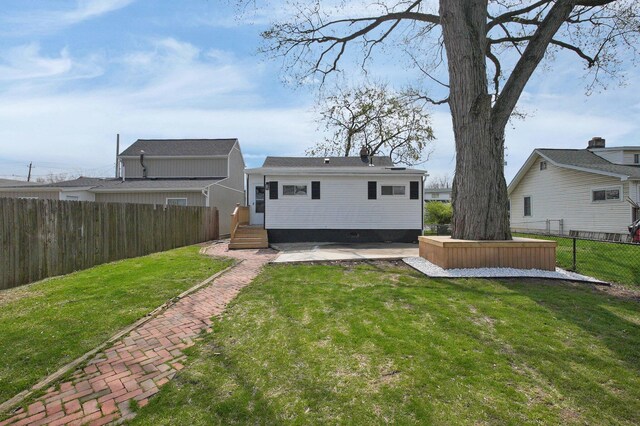 rear view of house featuring a fenced backyard and a lawn