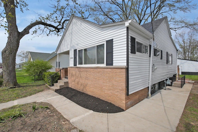 view of side of property with fence and brick siding