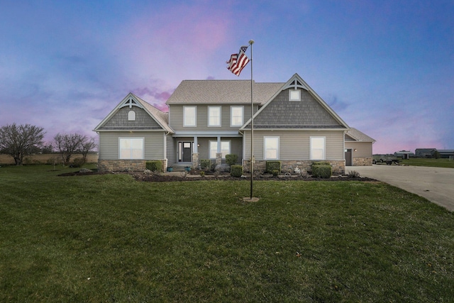 craftsman house with a lawn, stone siding, and concrete driveway