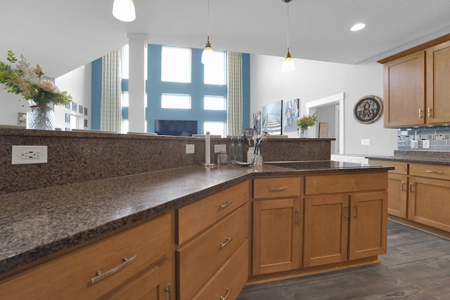 kitchen featuring black electric cooktop, backsplash, brown cabinets, decorative light fixtures, and dark wood-type flooring