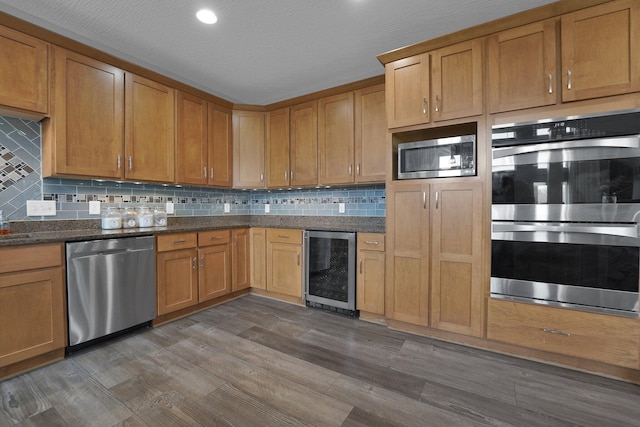 kitchen featuring decorative backsplash, appliances with stainless steel finishes, wood finished floors, and wine cooler