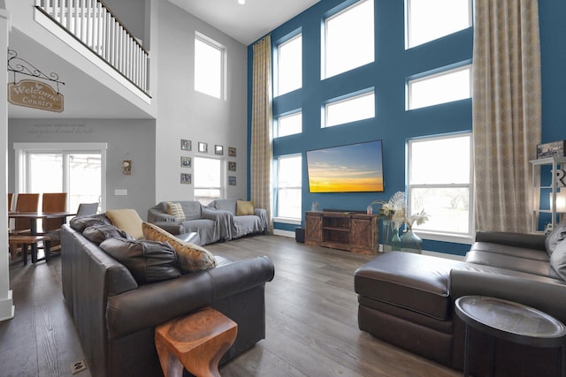 living area with wood finished floors and a towering ceiling