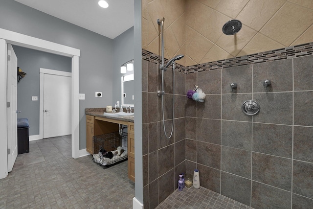 full bathroom featuring a tile shower, vanity, and recessed lighting