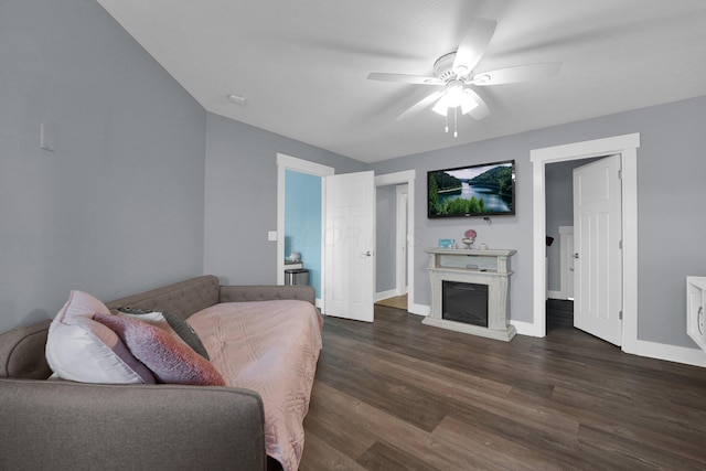 living area featuring baseboards, a ceiling fan, dark wood-type flooring, and a fireplace