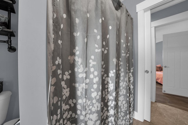 full bathroom with toilet, a shower with curtain, and tile patterned flooring
