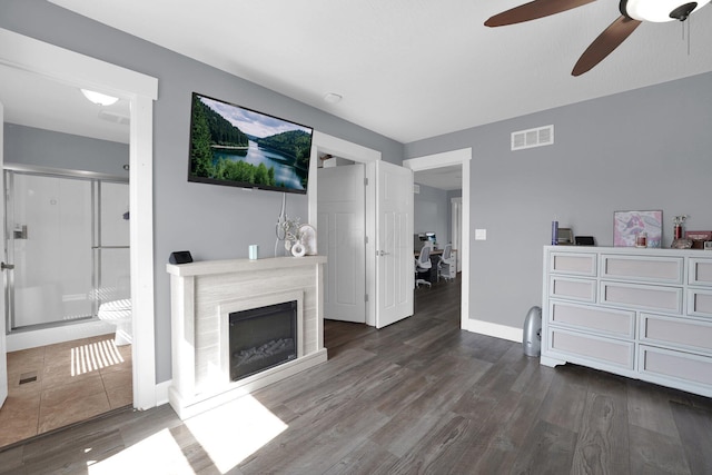 living room featuring dark wood-style floors, visible vents, baseboards, a fireplace, and ceiling fan
