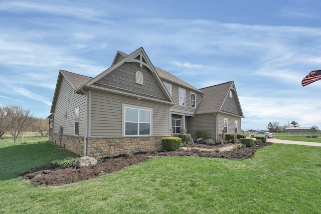 view of front facade featuring roof with shingles, stone siding, and a front yard