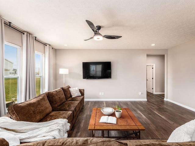living room with a textured ceiling, baseboards, wood finished floors, and a ceiling fan
