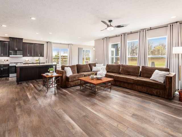 living room featuring dark wood-type flooring, a textured ceiling, ceiling fan, and recessed lighting
