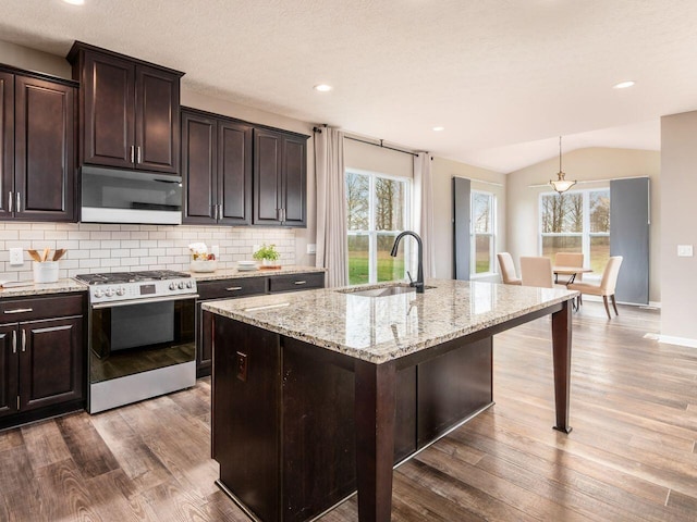 kitchen featuring gas stove, decorative backsplash, a sink, light wood finished floors, and light stone countertops
