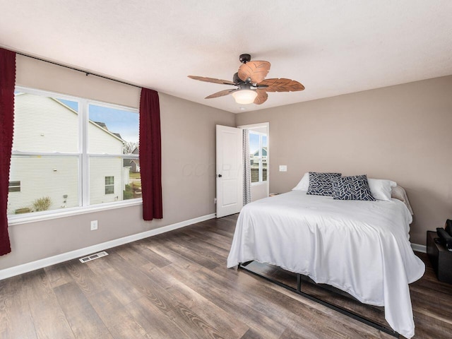 bedroom featuring baseboards, ceiling fan, visible vents, and wood finished floors