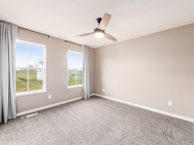 spare room featuring light carpet, baseboards, visible vents, and a ceiling fan