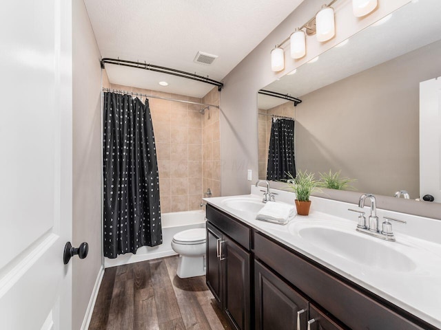 bathroom featuring shower / bath combination with curtain, wood finished floors, a sink, and visible vents