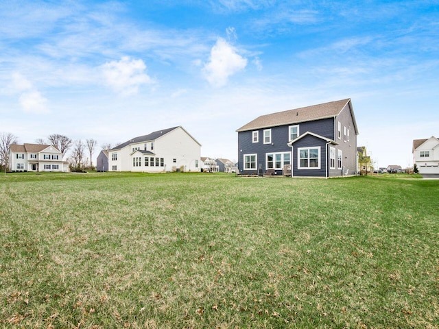 back of house featuring a lawn and a residential view
