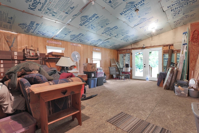 living area with lofted ceiling, wooden walls, and french doors
