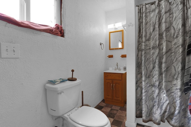 bathroom featuring tile patterned floors, vanity, toilet, curtained shower, and a textured wall