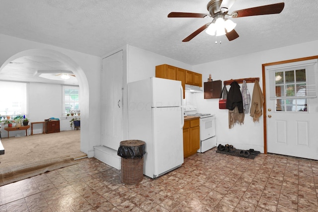 kitchen featuring white appliances, a ceiling fan, arched walkways, under cabinet range hood, and brown cabinets