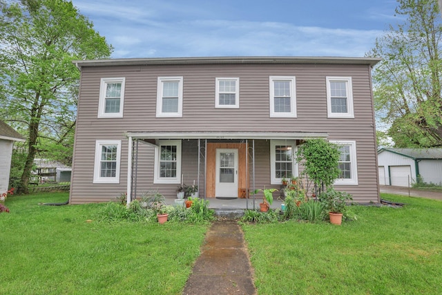 view of front of home with a porch, a front yard, and an outdoor structure