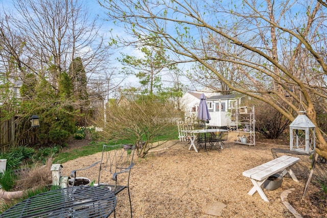 view of yard with outdoor dining area, an outdoor structure, and a storage unit