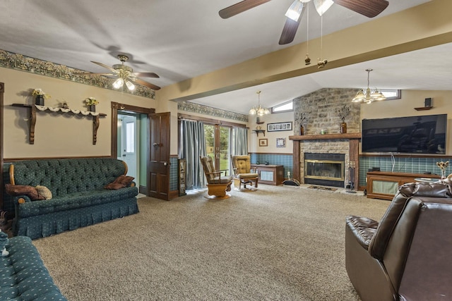carpeted living area featuring a large fireplace, a wainscoted wall, vaulted ceiling, and ceiling fan with notable chandelier