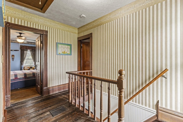stairway with visible vents, wallpapered walls, hardwood / wood-style flooring, and a textured ceiling