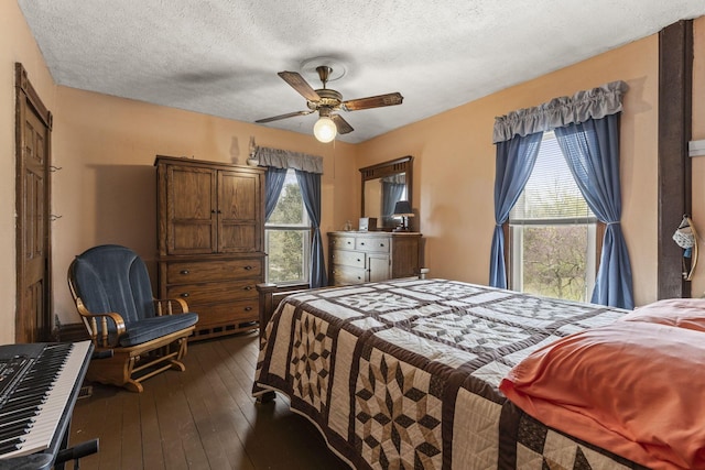 bedroom featuring dark wood-type flooring, a ceiling fan, and a textured ceiling
