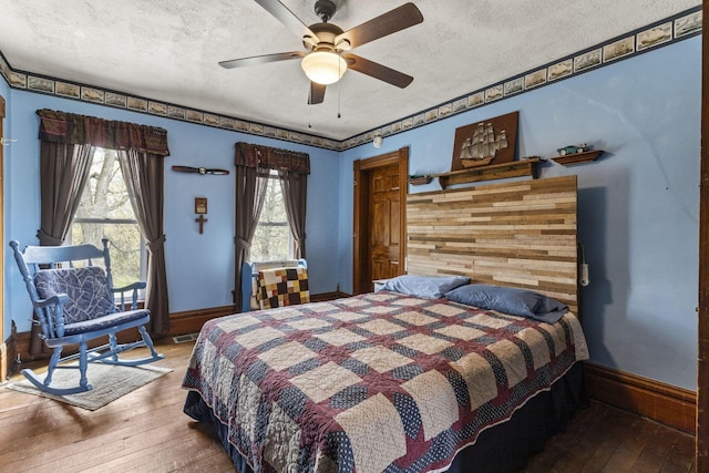 bedroom with hardwood / wood-style floors, a ceiling fan, and a textured ceiling