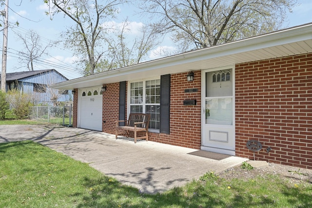 exterior space featuring fence, brick siding, and concrete driveway