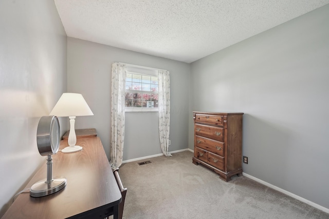 office space with light colored carpet, baseboards, a textured ceiling, and visible vents