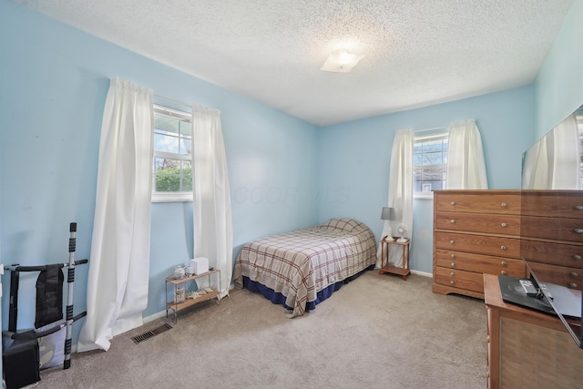 carpeted bedroom with baseboards, a textured ceiling, and visible vents