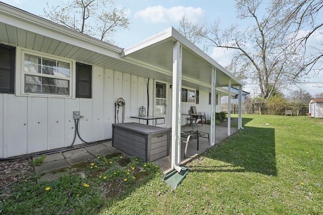 exterior space featuring board and batten siding, a patio area, a lawn, and fence
