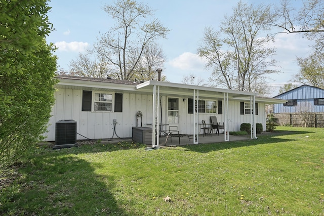 back of property with central air condition unit, fence, a patio area, board and batten siding, and a yard