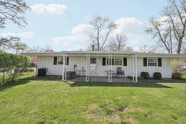 rear view of property featuring board and batten siding, a patio area, a lawn, and central AC