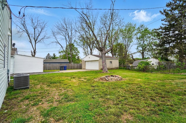 view of yard featuring an outbuilding, central air condition unit, fence, and a detached garage