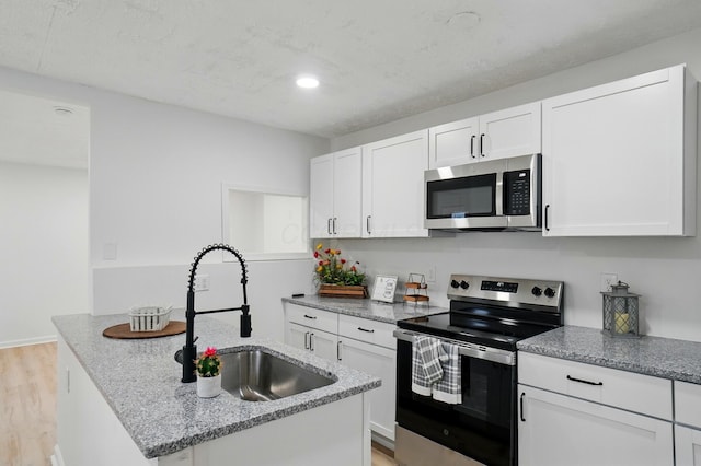 kitchen featuring white cabinetry, appliances with stainless steel finishes, a sink, and light wood-type flooring