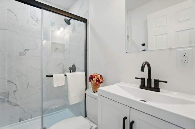 full bath featuring vanity, a marble finish shower, and toilet