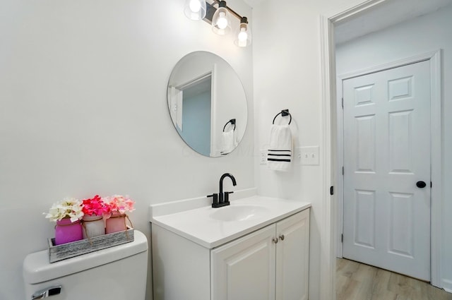 bathroom with toilet, wood finished floors, and vanity