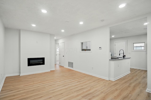 unfurnished living room with visible vents, recessed lighting, and light wood finished floors