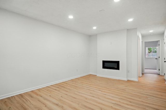 unfurnished living room with recessed lighting, light wood-style flooring, baseboards, and a fireplace