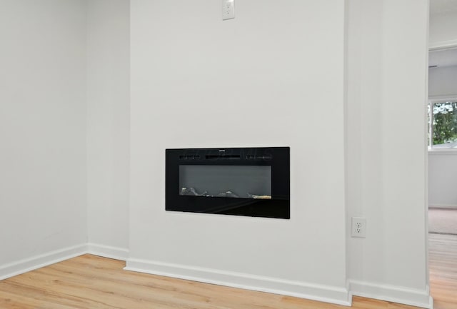 interior details with baseboards, a glass covered fireplace, and wood finished floors