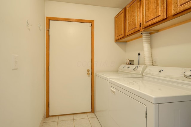 laundry area featuring separate washer and dryer, light tile patterned floors, baseboards, and cabinet space