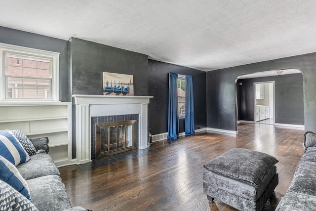 624 W 1st St, Springfield, OH 45504 - living room with a textured ceiling, arched walkways, wood finished floors, a fireplace with flush hearth, and baseboards