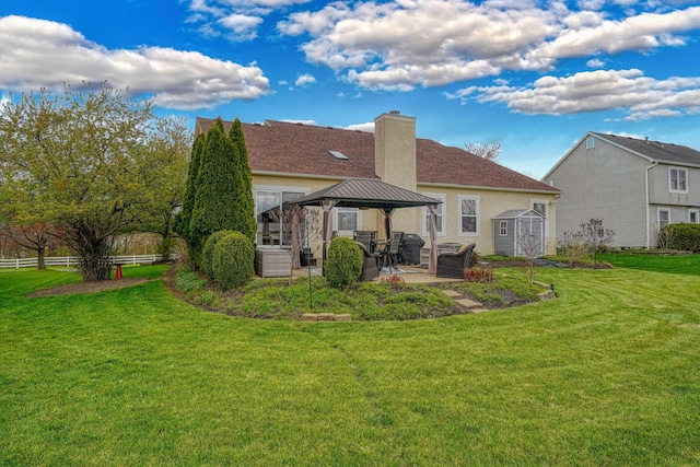 back of house featuring a patio, a chimney, a gazebo, fence, and a lawn