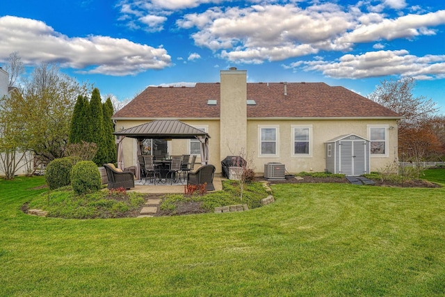 back of house with central AC unit, a patio area, a gazebo, a lawn, and a chimney