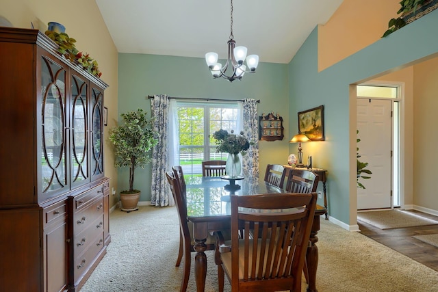 carpeted dining room featuring baseboards, a notable chandelier, and vaulted ceiling