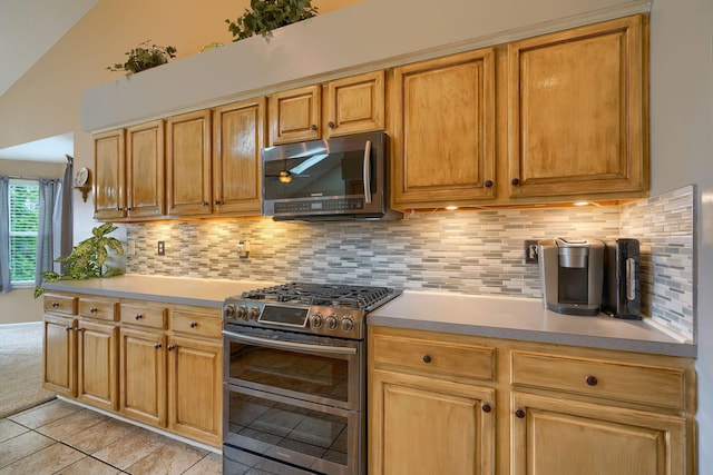 kitchen featuring stainless steel appliances, light tile patterned floors, light countertops, and decorative backsplash