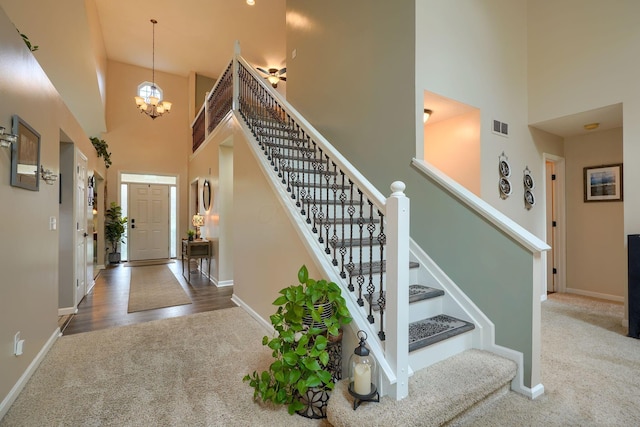 foyer featuring baseboards, a towering ceiling, visible vents, and carpet floors