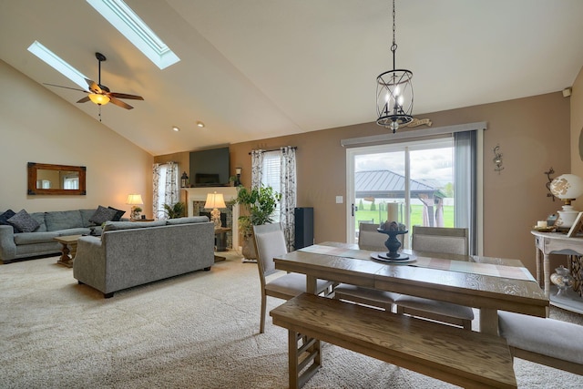 dining area featuring a skylight, high vaulted ceiling, light colored carpet, and a ceiling fan