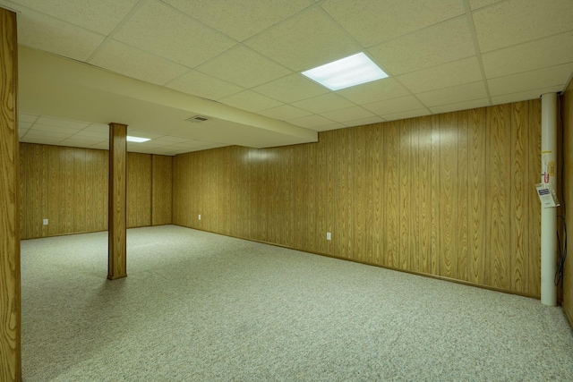 finished below grade area with wooden walls, carpet floors, and a paneled ceiling